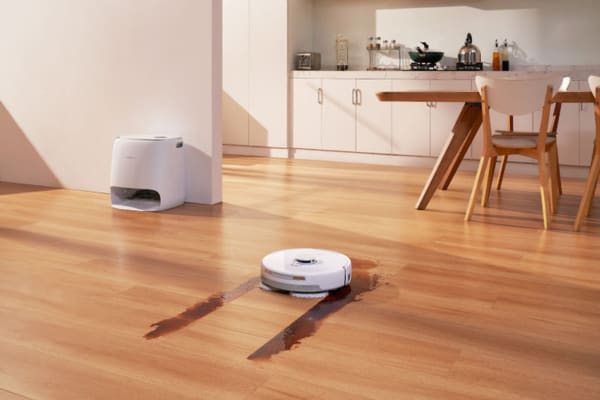 A robot vacuum cleans a hardwood floor, demonstrating its effectiveness on these surfaces.