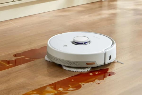 A robot vacuum cleaning a hardwood floor with spilled liquid, showcasing how effective they are.