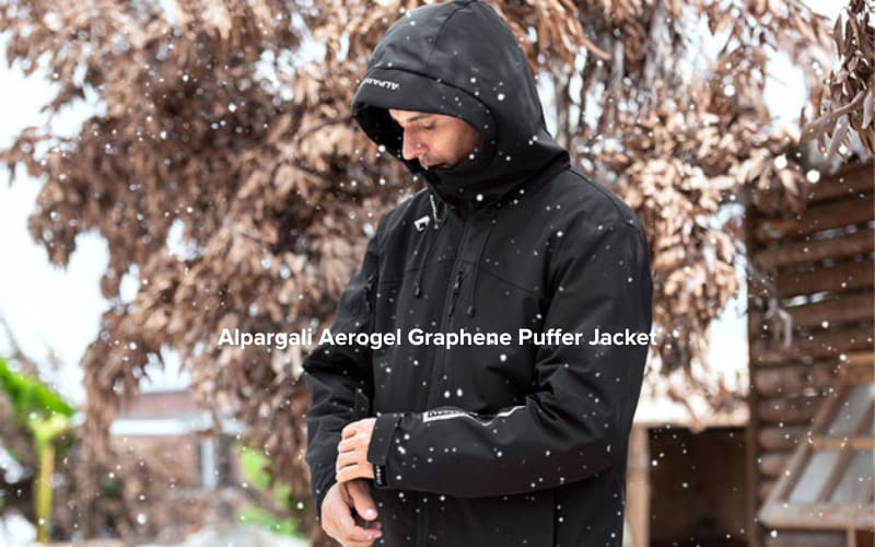 A person in a black puffer jacket stands in the snow, ideal for Yellowstone hikes in winter.