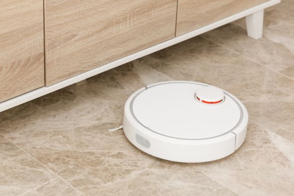 A robot vacuum cleaner designed for efficient cleaning on marble floors, quietly operating under furniture.