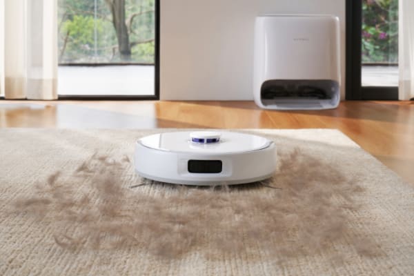 A robot vacuum picks up pet hair from a carpet, showcasing its effectiveness in clean home maintenance.