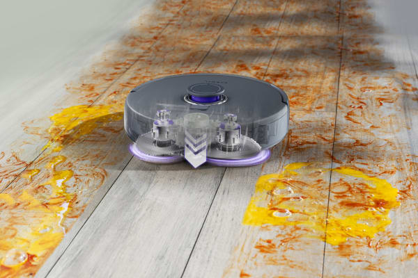 A robot vacuum navigating a floor covered in stains, raising the question: Do robot vacuums really clean your floors effectively?