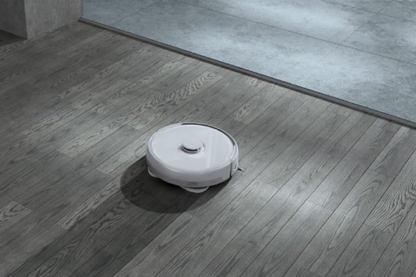 A robotic vacuum cleaner on wooden flooring, showcasing how to use vacuum cleaner technology effectively.