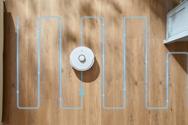 A robot vacuum navigates a wooden floor, demonstrating how to teach your robot vacuum to avoid obstacles.