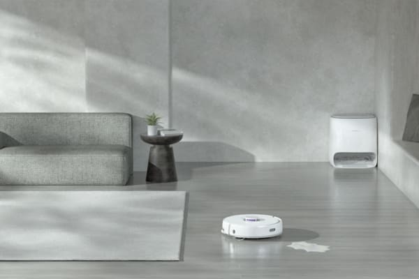 A modern living room features a robot vacuum near a liquid spill, raising the question: Can You Vacuum Liquid Spills with a Robot Vacuum?