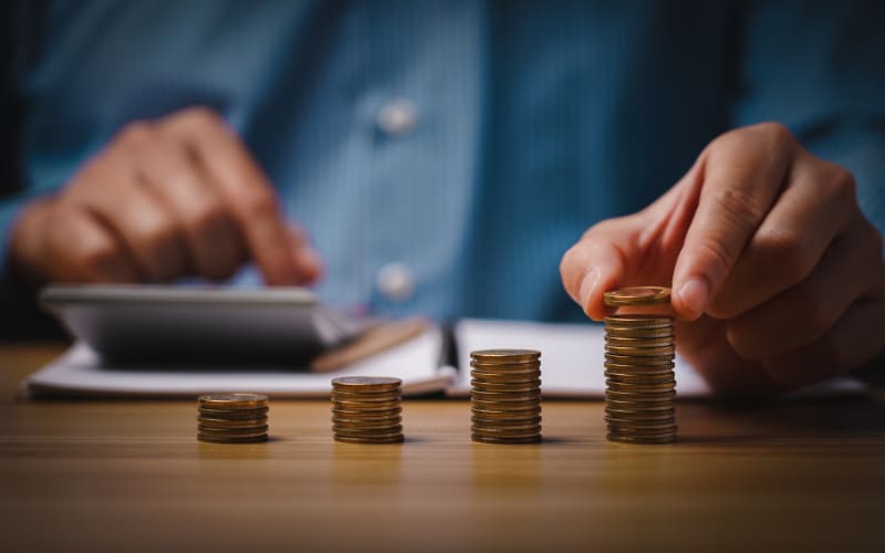 A person calculates finances on a calculator while organizing coins, highlighting automatic identification and data capture processes.