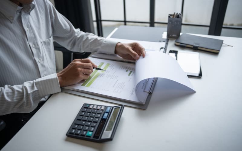 A professional at a desk reviews documents, focusing on automatic identification and data capture processes with a calculator nearby.