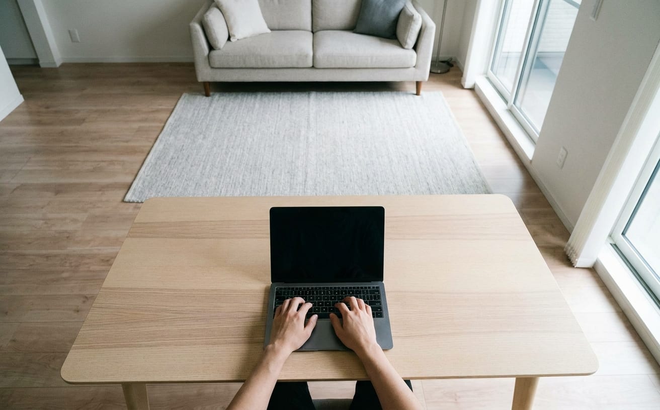 シンプルで整理された部屋でノートパソコンを使い、掃除ができる人の特徴が際立つ瞬間。