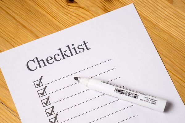 A neatly organized home cleaning checklist on a wooden surface with a white marker.