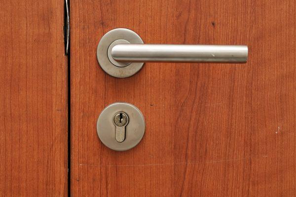 A close-up of a door handle and lock on a wooden door, ideal for a home cleaning checklist.