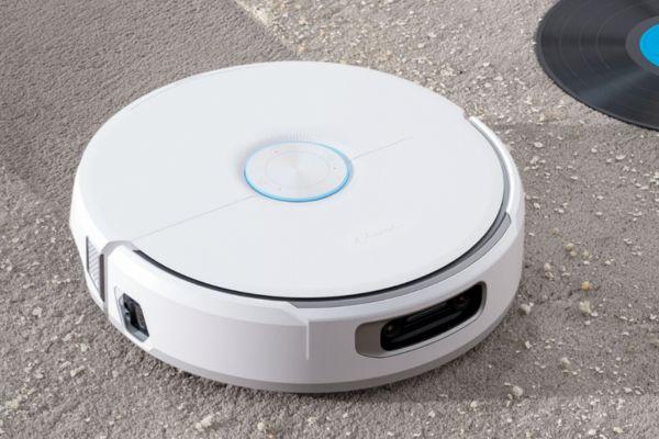A white robotic vacuum cleaner on a textured surface, demonstrating the concept of what is spot cleaning for effective surface maintenance.
