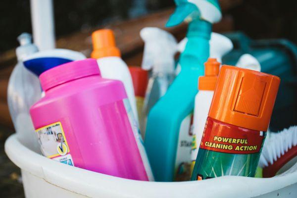 A collection of various cleaning supplies in a bucket, illustrating what is spot cleaning for quick household tasks.