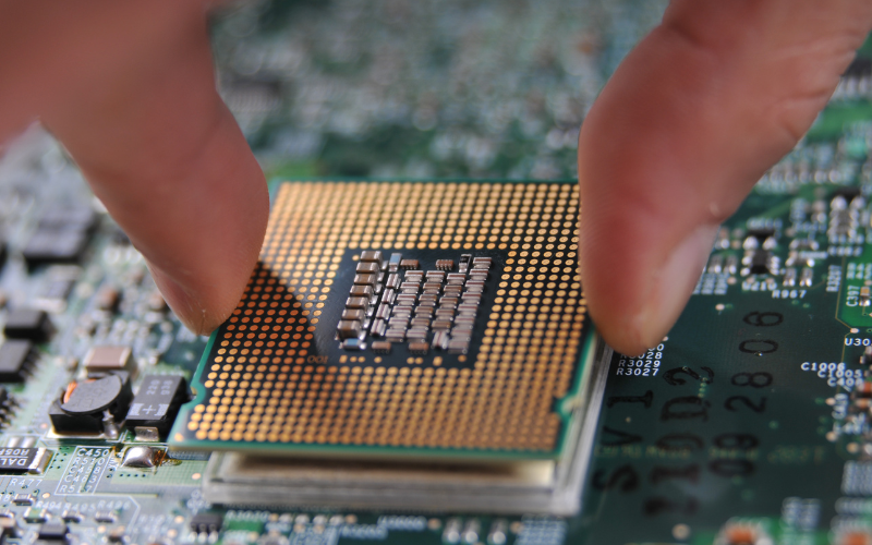 A close-up of a hand placing a processor onto a circuit board, highlighting the competition between MediaTek vs Snapdragon.