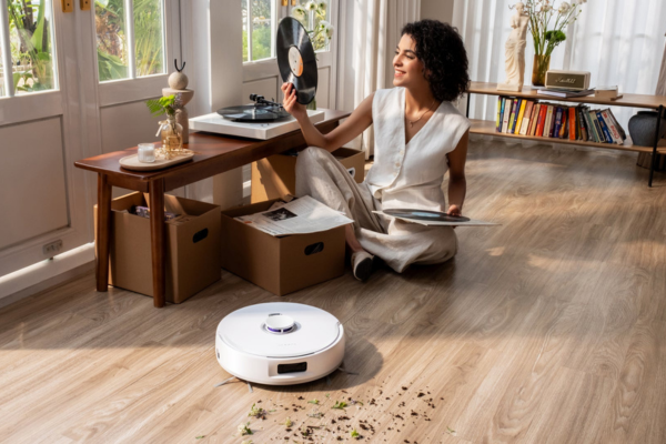 A woman enjoys music while a robot vacuum cleans nearby, showcasing the convenience of names for robot vacuum.
