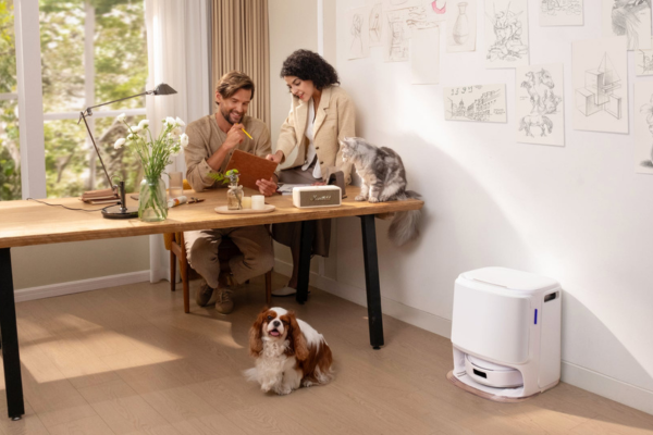 A couple enjoys time together in a home office with pets nearby, while exploring names for robot vacuum options.