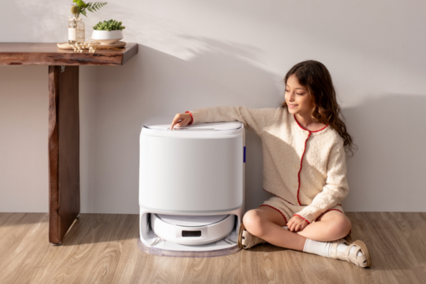 A girl sits beside a robot vacuum, exploring cute names for robot vacuum while enjoying her cozy indoor space.