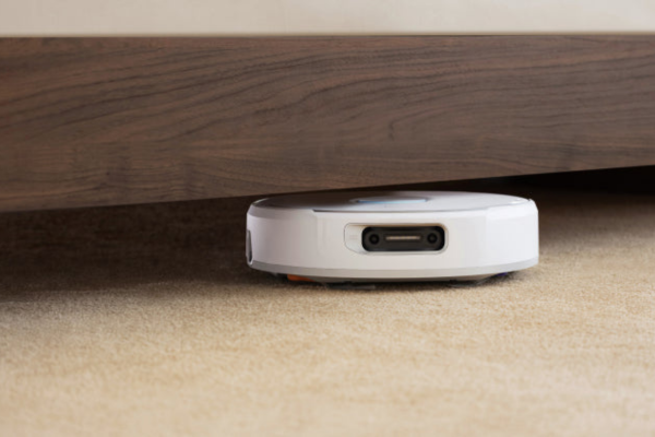 A thinnest robot vacuum effortlessly cleans beneath furniture, showcasing its sleek design and maneuverability on carpet.