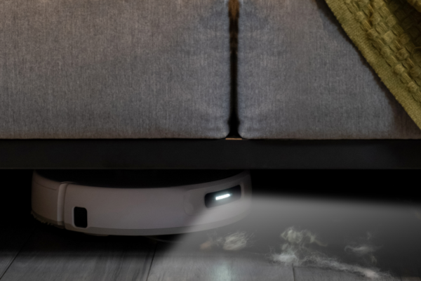 A sleek, modern robot vacuum glides under a sofa, showcasing its design as the thinnest robot vacuum available.