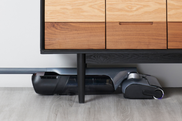 A sleek, modern lightweight vacuum tucked under a stylish wooden dresser, showcasing the best lightweight vacuum design.
