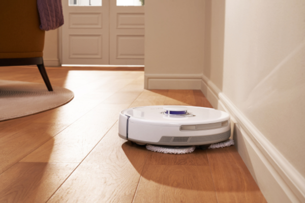 A white robot vacuum effectively cleaning corners and edges of a wooden floor, showcasing the best features for thorough cleaning.