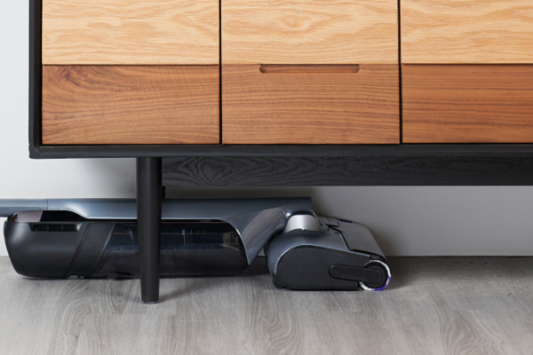 A modern living space featuring the best anti hair wrap vacuum tucked beneath a stylish wooden cabinet.