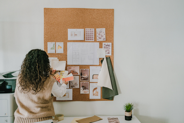 A woman organizes design ideas on a corkboard, preparing for cleaning after a party with fresh inspiration and creativity.