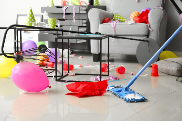 Colorful party remnants scatter across the floor, emphasizing the chaos of cleaning after a party.