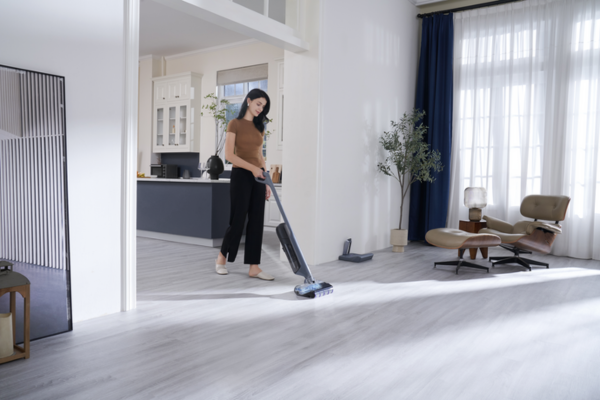 A woman cleans hardwood floors with a vacuum mop, showcasing the best vacuum mop for hardwood floors in a stylish room.