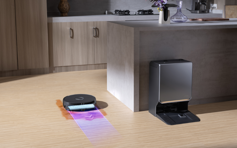 A robotic cleaner is showcasing narwal flow 2 vs flow, with cleaning solutions displayed on a wooden floor in a modern kitchen.