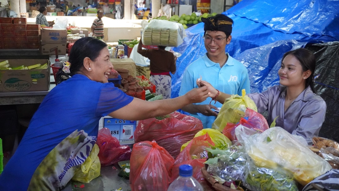 Meanwhile, a lively conversation unfolds at a Balinese local market as vendors and visitors exchange goods and smiles among fresh produce, offerings, and traditional ingredients.