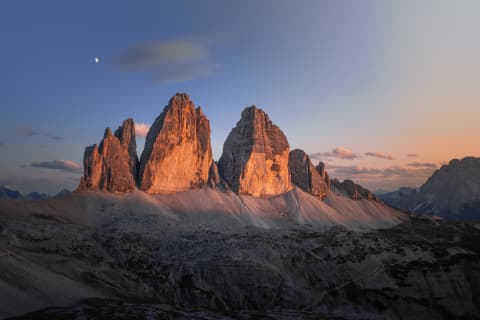 Wschód księżyca nad rozświetlonymi Tre Cime di Lavaredo