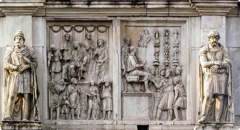 Relief sculpture depicting historical figures and scenes, flanked by two large statues on either side.