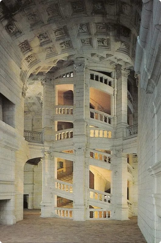 A grand, spiraling staircase made of white stone, surrounded by ornate architectural details and soft lighting in a large, open space.