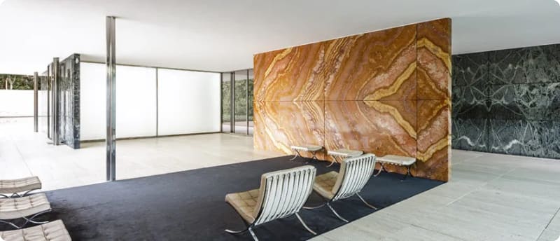 Interior of a modern architectural space featuring a striking orange onyx wall, black marble accents, and minimalist furniture.