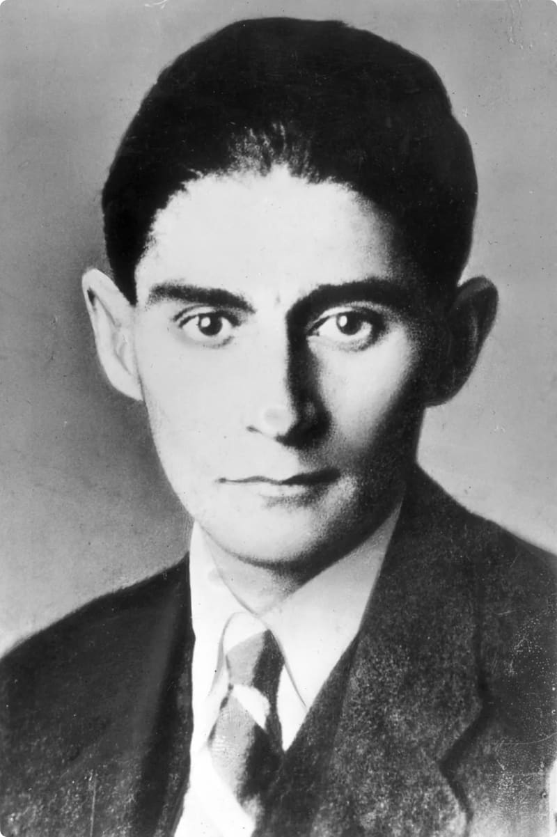 Black and white portrait of a young man with dark hair, wearing a suit and tie, looking directly at the camera.