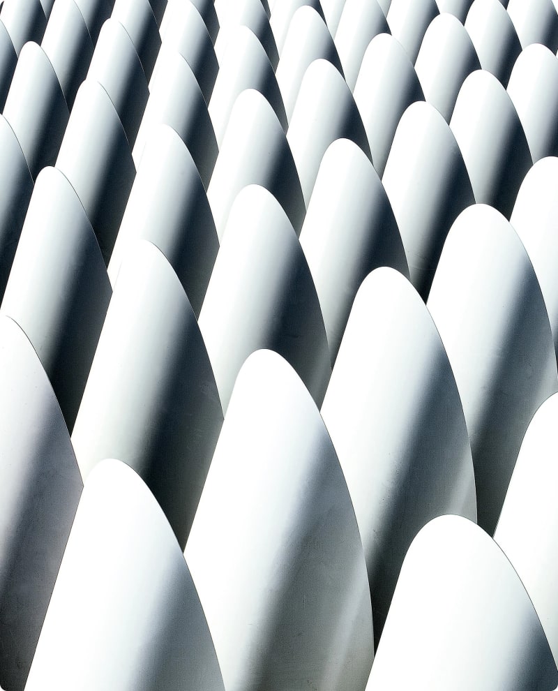A close-up of a series of white, curved, overlapping shapes creating a wave-like pattern.