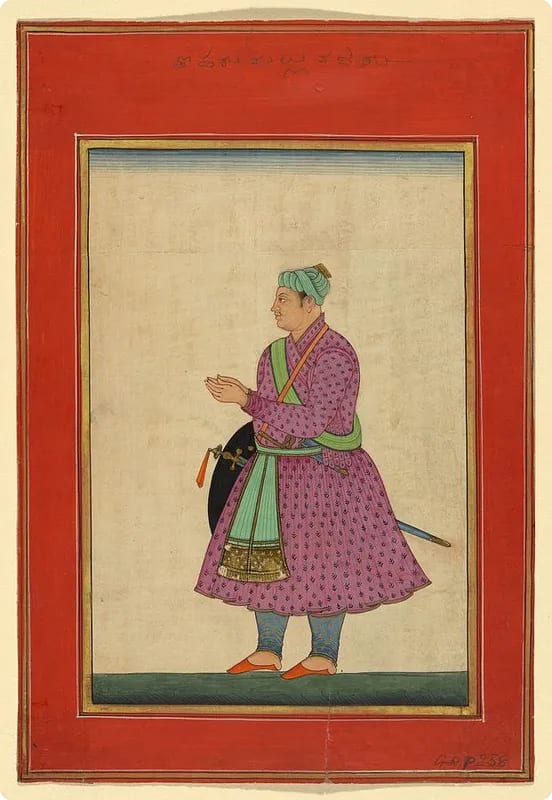 A historical figure in traditional attire, wearing a purple patterned robe and a green sash, holding a shield and sword, set against a red border.