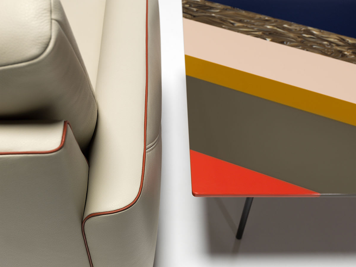 Gros plan des canapés Thalia 9182 en cuir de Beging à côté d'une table moderne avec des motifs géométriques colorés. Gros plan des canapés Thalia 9182 en cuir de Beging à côté d'une table moderne avec des motifs géométriques colorés.