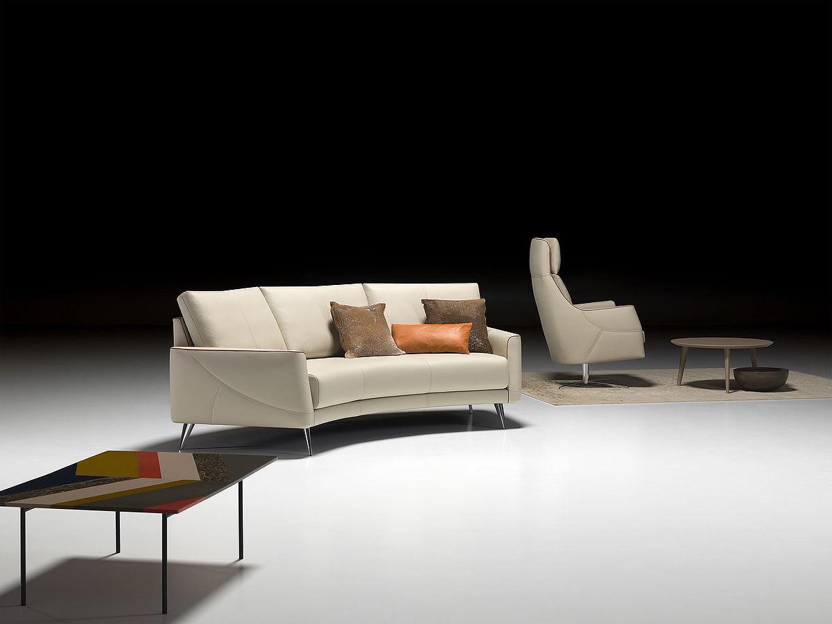 Salon moderne avec le canapé Thalia 9182 dans de la crème, complété par un fauteuil, une table basse et un oreiller accent sur un étage blanc. Salon moderne avec le canapé Thalia 9182 dans de la crème, complété par un fauteuil, une table basse et un oreiller accent sur un étage blanc.