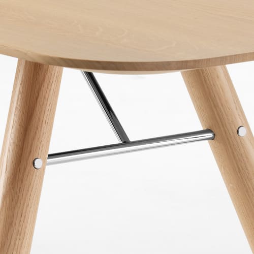 Gros plan de l'os en bois de la table à manger Akio avec un support en métal et un siège en bois clair. Gros plan de l'os en bois de la table à manger Akio avec un support en métal et un siège en bois clair.