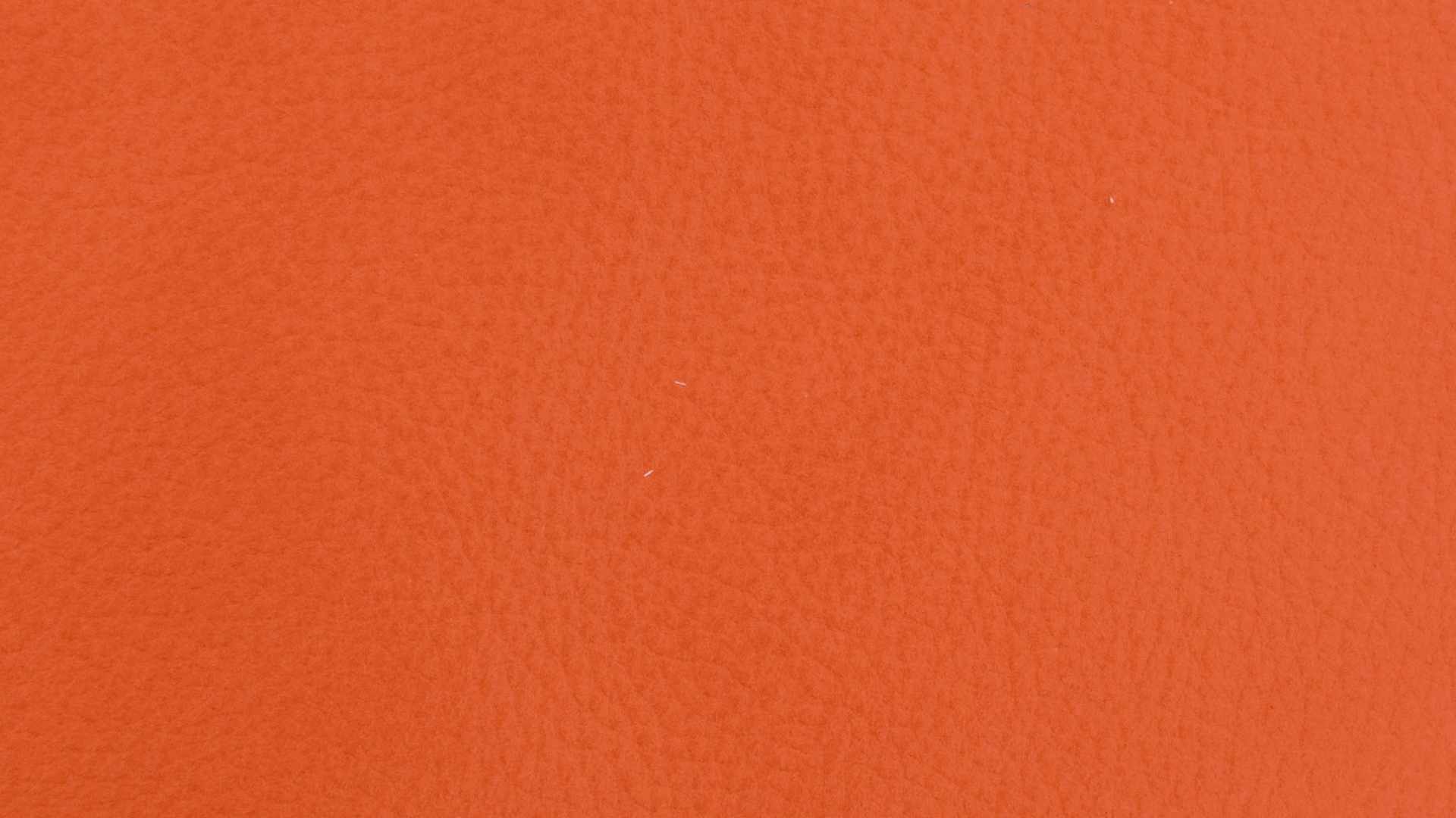 Nahaufnahme der strukturierten orangefarbenen Lederoberfläche des Koinor Funktionssofas Experio. Nahaufnahme der strukturierten orangefarbenen Lederoberfläche des Koinor Funktionssofas Experio.