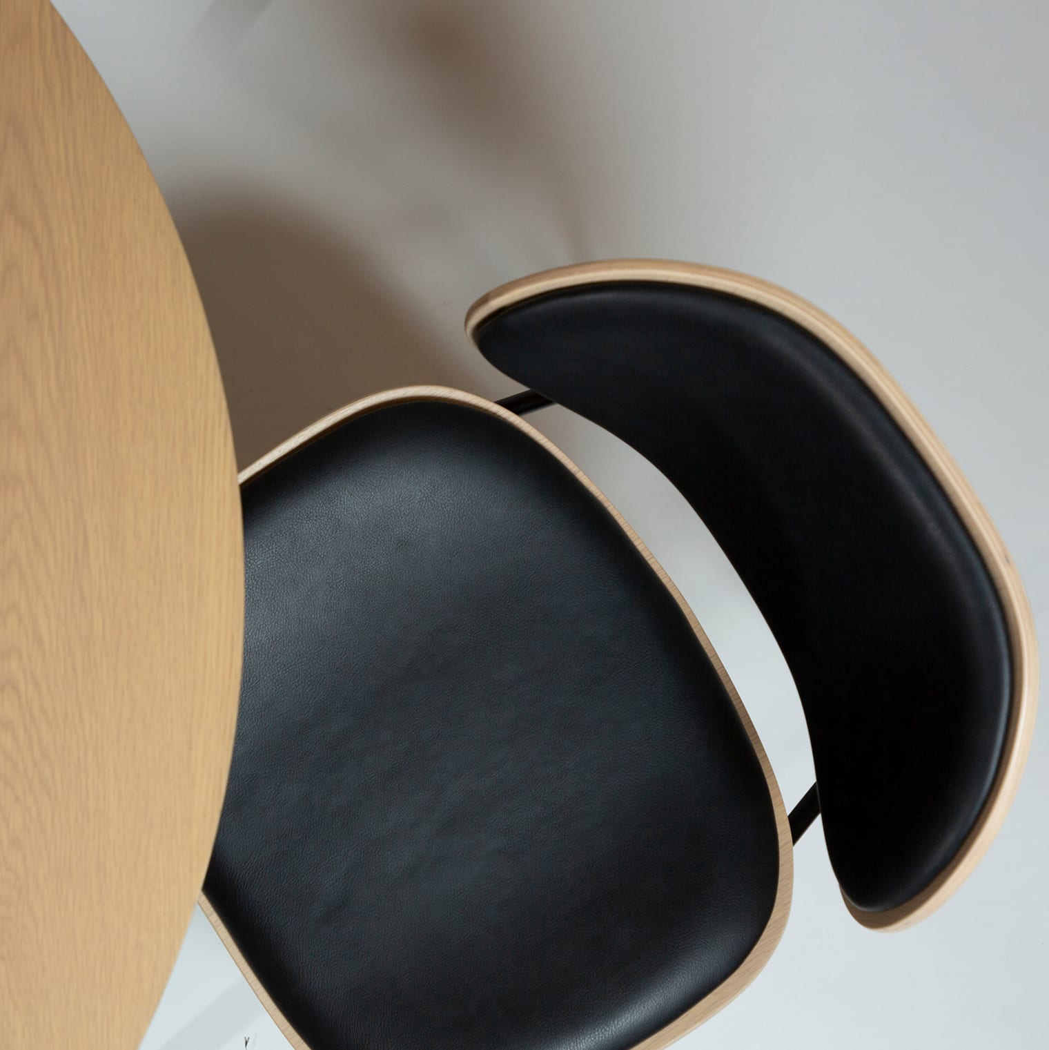 Tisch Ooid mit Clementina-Stühlen, von oben gesehen, neben einem runden Holztisch auf hellem Boden. Tisch Ooid mit Clementina-Stühlen, von oben gesehen, neben einem runden Holztisch auf hellem Boden.