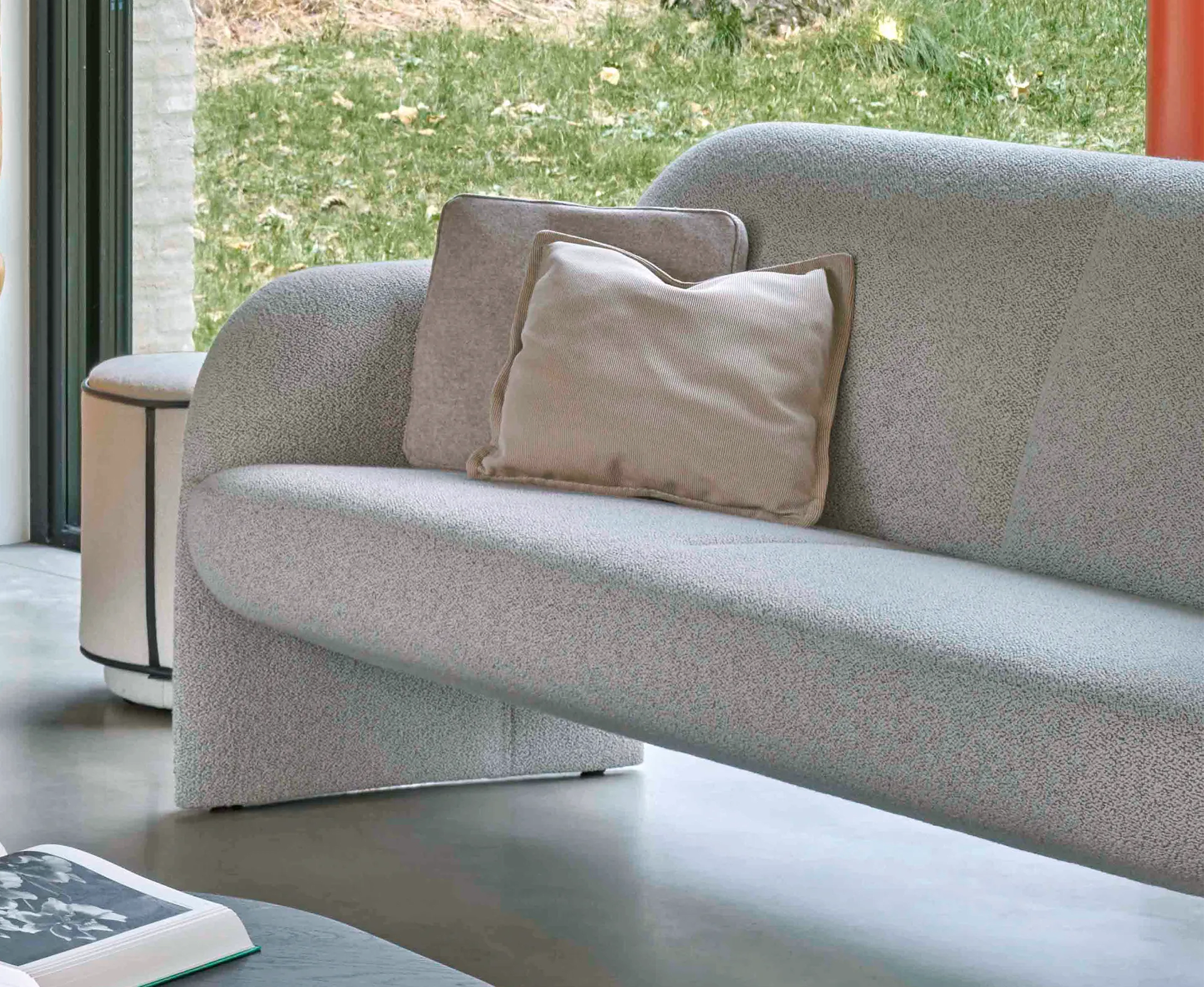 Leolux Sofa Modius in Hellgrau mit zwei beigen Kissen, positioniert an einem Fenster mit Blick auf eine grüne Wiese. Leolux Sofa Modius in Hellgrau mit zwei beigen Kissen, positioniert an einem Fenster mit Blick auf eine grüne Wiese.