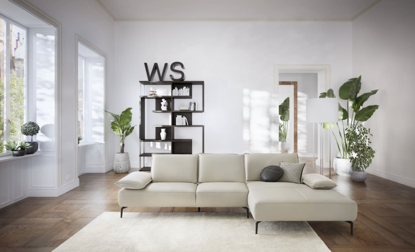 Modernes Wohnzimmer mit einem W.Schillig Sofa Caipirinjaa 16568 in Beige, großen Fenstern, Grünpflanzen und einem schwarzen Regal mit "WS"-Dekor. Modernes Wohnzimmer mit einem W.Schillig Sofa Caipirinjaa 16568 in Beige, großen Fenstern, Grünpflanzen und einem schwarzen Regal mit "WS"-Dekor.