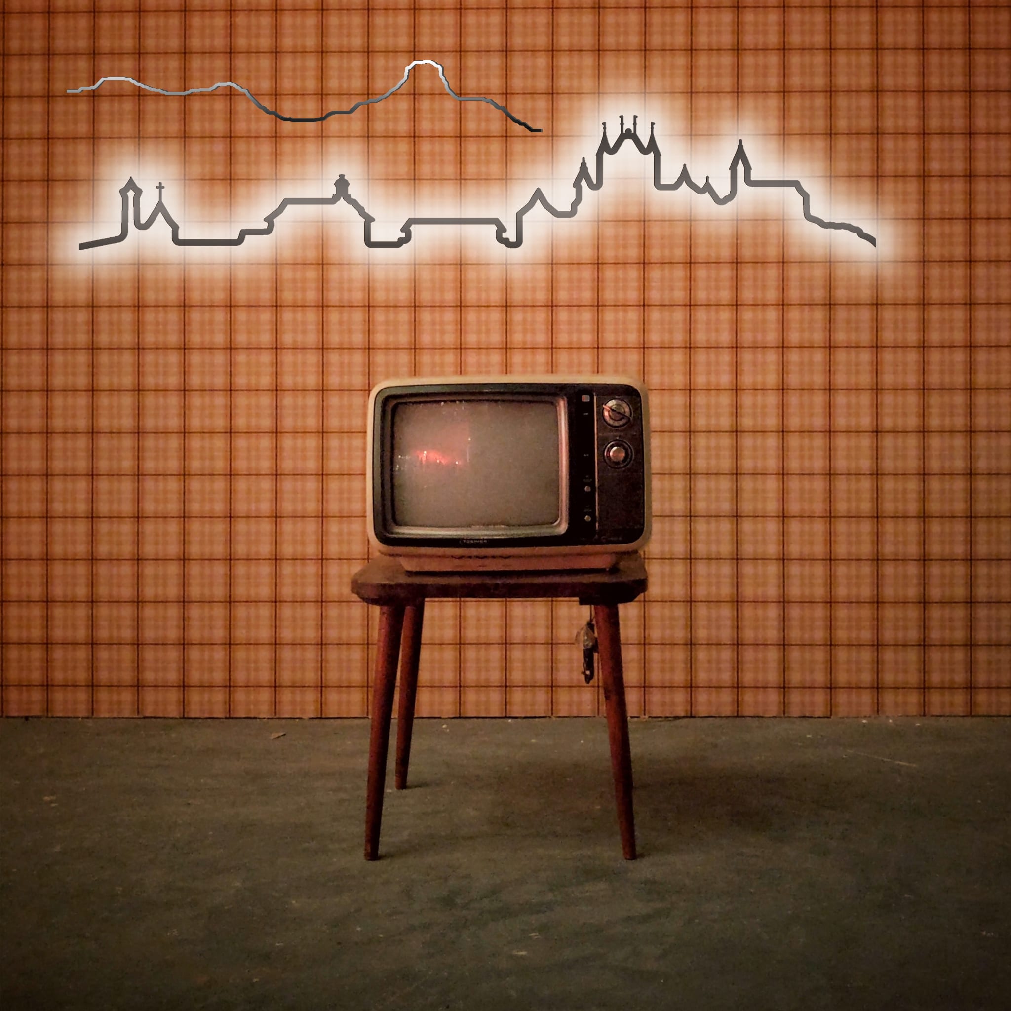 Die Kontura City Bern wird auf einem Holzständer präsentiert, der mit einer karierten Tapete versehen ist, über der eine Stadt- und Berglandschaft zu sehen ist.