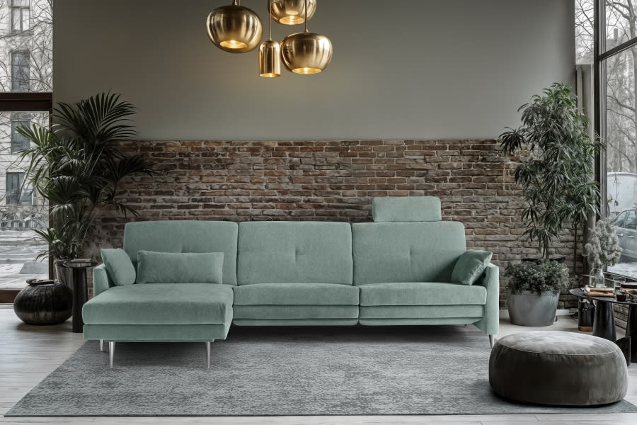Modernes Wohnzimmer mit dem Horst Sofa Chiasso in Grün, einer Backsteinwand, üppigen Pflanzen, einem grauen Teppich und goldenen Pendelleuchten. Modernes Wohnzimmer mit dem Horst Sofa Chiasso in Grün, einer Backsteinwand, üppigen Pflanzen, einem grauen Teppich und goldenen Pendelleuchten.