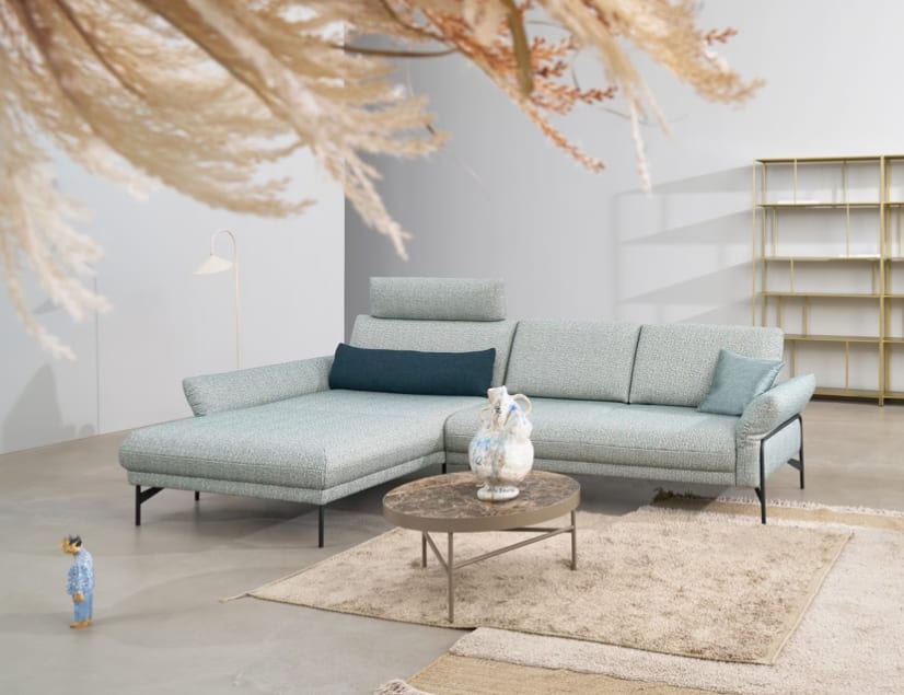 Modernes Wohnzimmer mit dem hellblauen Sektionssofa Himolla Polstergruppe Nova 1370, ergänzt durch einen runden Couchtisch, einen Teppich und ein minimalistisches Dekor. Modernes Wohnzimmer mit dem hellblauen Sektionssofa Himolla Polstergruppe Nova 1370, ergänzt durch einen runden Couchtisch, einen Teppich und ein minimalistisches Dekor.