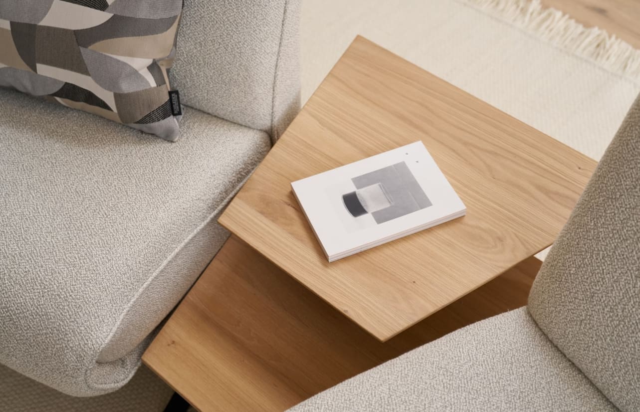 Ein Buch mit geometrischem Einband ruht auf einem Holztisch zwischen zwei Himolla Trapezsofa 4362 Loungesesseln mit hellen Polstern. Ein Buch mit geometrischem Einband ruht auf einem Holztisch zwischen zwei Himolla Trapezsofa 4362 Loungesesseln mit hellen Polstern.