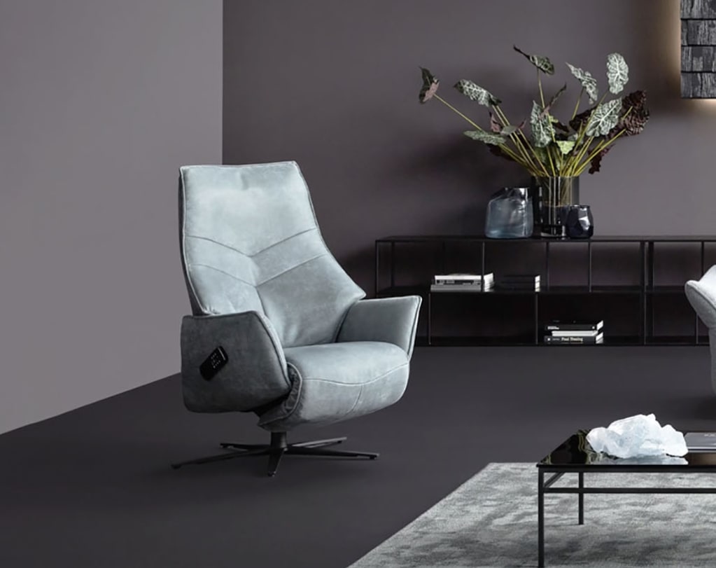 Der Himolla Relaxsessel S-Loung7911, ein hellgrauer Drehsessel, steht in einem modernen Wohnzimmer mit dunklen Wänden, einem minimalistischen Tisch und blättrigem Pflanzendekor. Der Himolla Relaxsessel S-Loung7911, ein hellgrauer Drehsessel, steht in einem modernen Wohnzimmer mit dunklen Wänden, einem minimalistischen Tisch und blättrigem Pflanzendekor.