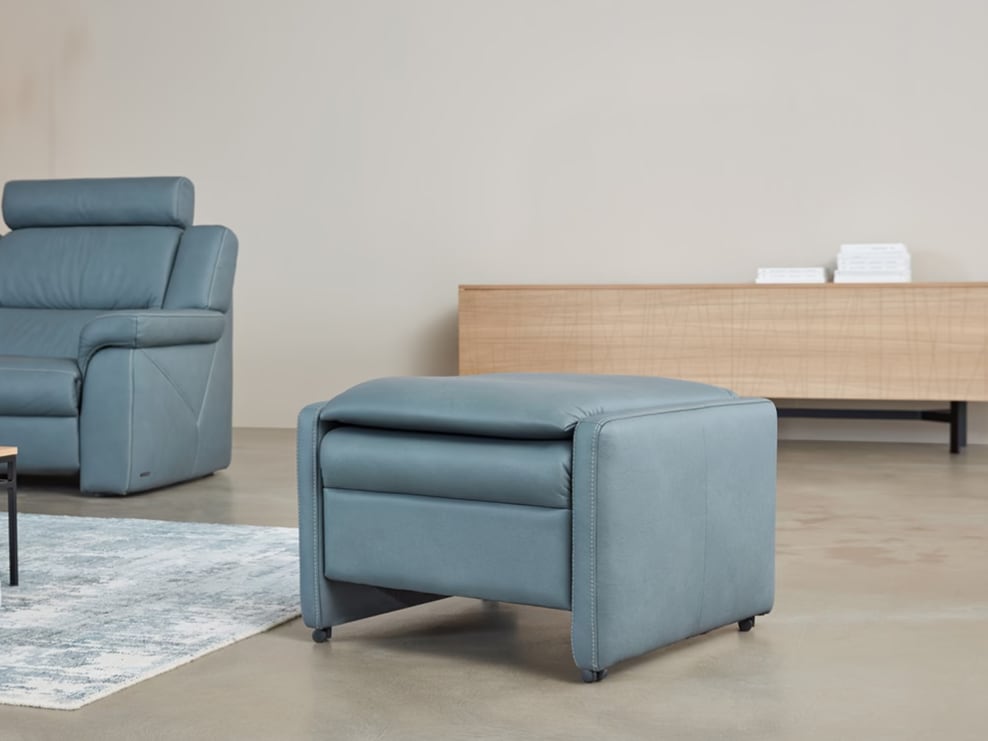Der Himolla Einzelhocker/Sessel 7112 in blauem Leder ist in einem modernen Wohnzimmer zu sehen, zusammen mit einem passenden Sofa und einem Holzsideboard im Hintergrund. Der Himolla Einzelhocker/Sessel 7112 in blauem Leder ist in einem modernen Wohnzimmer zu sehen, zusammen mit einem passenden Sofa und einem Holzsideboard im Hintergrund.